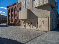 cobblestone driveway surrounded by modern buildings on sunny day with sun reflecting onto the windows