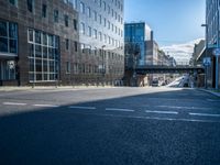 the empty road is surrounded by tall buildings in the area, which has a bridge in the middle of it