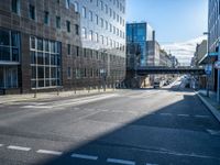 the empty road is surrounded by tall buildings in the area, which has a bridge in the middle of it