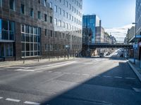 the empty road is surrounded by tall buildings in the area, which has a bridge in the middle of it