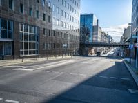 the empty road is surrounded by tall buildings in the area, which has a bridge in the middle of it