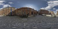 circular photograph showing multiple different buildings in a downtown area with a cobblestone street