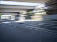 a motion blurry shot of a street with buildings and a bridge in the background