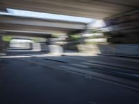 a motion blurry shot of a street with buildings and a bridge in the background