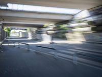 a motion blurry shot of a street with buildings and a bridge in the background