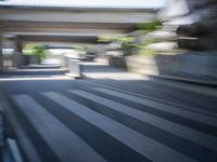 a motion blurry shot of a street with buildings and a bridge in the background