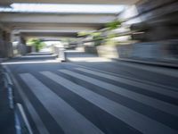 a motion blurry shot of a street with buildings and a bridge in the background