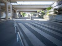 a motion blurry shot of a street with buildings and a bridge in the background