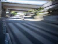 a motion blurry shot of a street with buildings and a bridge in the background