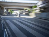 a motion blurry shot of a street with buildings and a bridge in the background
