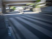 a motion blurry shot of a street with buildings and a bridge in the background