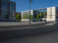 a street light next to an empty road in front of a building with a traffic light on top of it