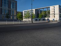 a street light next to an empty road in front of a building with a traffic light on top of it