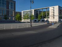 a street light next to an empty road in front of a building with a traffic light on top of it