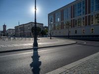 a street light next to an empty road in front of a building with a traffic light on top of it