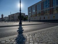 a street light next to an empty road in front of a building with a traffic light on top of it