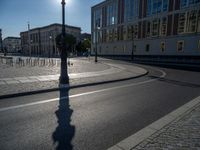 a street light next to an empty road in front of a building with a traffic light on top of it