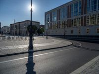 a street light next to an empty road in front of a building with a traffic light on top of it