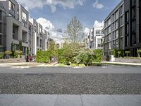 a residential complex with several apartments in the background and a couple of trees in the middle