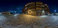 fisheye looking into a street at night with people walking on sidewalk in front of it