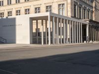 a photo taken outside of an old building with columns and pillars on the street side