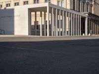 a photo taken outside of an old building with columns and pillars on the street side