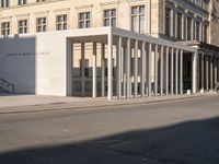 a photo taken outside of an old building with columns and pillars on the street side