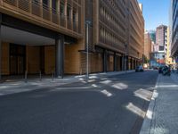 a road through which is a large modern building with an awning over it's entrance