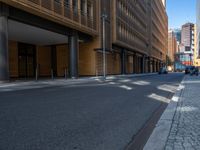 a road through which is a large modern building with an awning over it's entrance