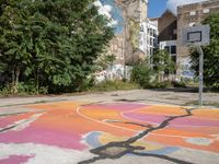 a basketball court in a rundown neighborhood surrounded by trees and graffiti on the walls