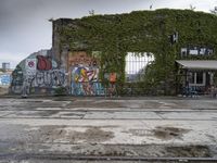 graffiti, trees and people in the background at a building, with no roof or windows