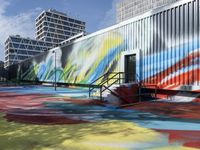 a multicolored painting on a steel container wall next to stairs and street lights