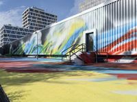 a multicolored painting on a steel container wall next to stairs and street lights