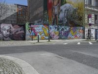 the street in front of the graffiti covered building is empty and empty, but has two rows