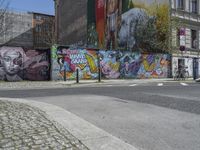 the street in front of the graffiti covered building is empty and empty, but has two rows