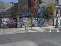 the street in front of the graffiti covered building is empty and empty, but has two rows