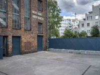 a basketball court with black fence around it in front of brick building and tall buildings