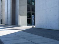 the man is sitting on his luggage in front of an empty building on the sidewalk