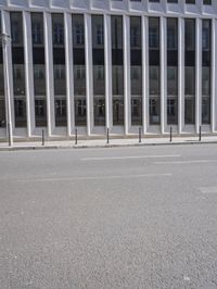 a long white crosswalk along the street in front of a tall building with a lot of windows