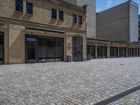 the sidewalk is paved with stones and has a bench in front of it, with no people inside