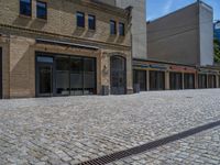 the sidewalk is paved with stones and has a bench in front of it, with no people inside