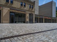 the sidewalk is paved with stones and has a bench in front of it, with no people inside