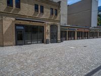 the sidewalk is paved with stones and has a bench in front of it, with no people inside