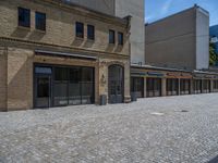 the sidewalk is paved with stones and has a bench in front of it, with no people inside