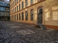 a sidewalk with chairs next to the brick building on the side, some have stairs and some buildings in the background