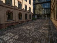 a sidewalk with chairs next to the brick building on the side, some have stairs and some buildings in the background