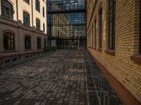 a sidewalk with chairs next to the brick building on the side, some have stairs and some buildings in the background