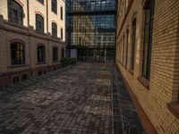 a sidewalk with chairs next to the brick building on the side, some have stairs and some buildings in the background