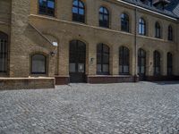 the sidewalk is paved with stones and has a bench in front of it, with no people inside