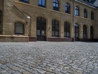 the sidewalk is paved with stones and has a bench in front of it, with no people inside